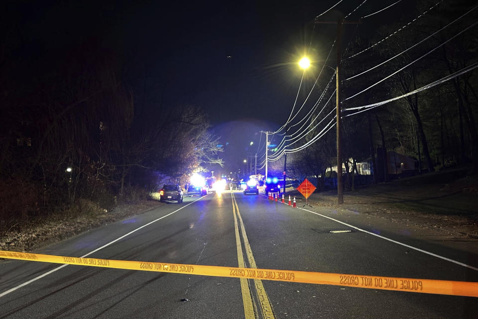 Police tape blocks a roadway in Waltham, Mass., after a person in a vehicle struck and injured utility workers before stealing a police cruiser, Wednesday, Dec. 6, 2023. The driver in the suburb of Boston crashed the cruiser before being captured, law enforcement officials said. (AP Photo/Michael Casey)