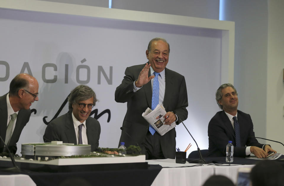 Mexican billionaire Carlos Slim, standing, jokes with journalists at the end of a news conference in Mexico City, Wednesday, Oct. 16, 2019. Slim says he supports President Andrés Manuel López Obrador's objectives. (AP Photo/Fernando Llano)