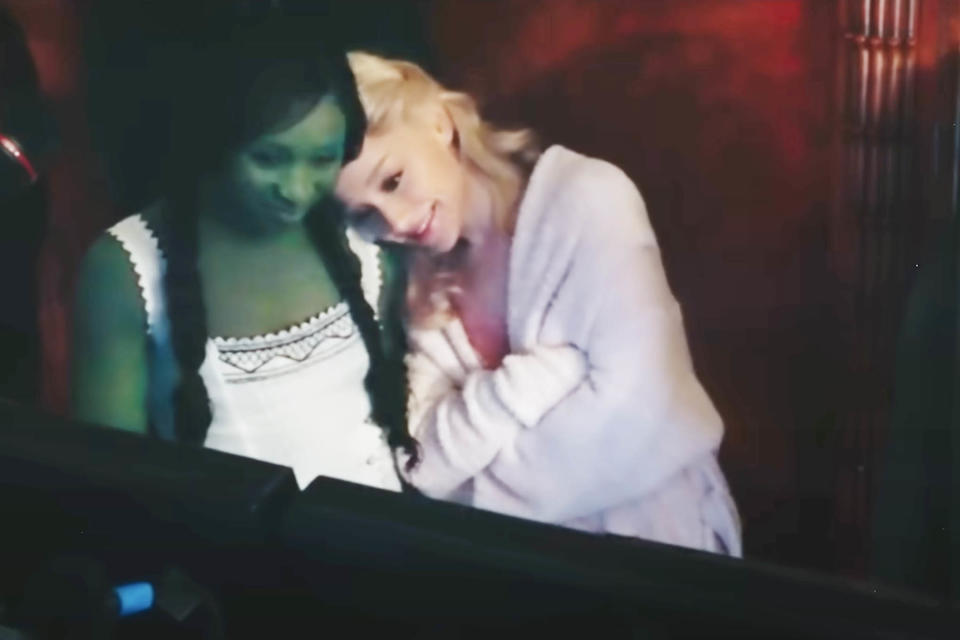Ariana Grande resting her head on Cynthia Erivo's shoulder behind the scenes of Wicked