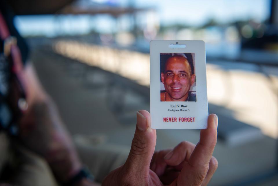 Jackson firefighter Chris Hansen shows the card of Carl V. Bini, a NYFD firefighter who died while rescuing victims in the 9/11 attacks, that he keeps inside his gear after the 2nd Annual Patriot Day Memorial Stair Climb at the Ballpark at Jackson on Saturday, Sept. 9, 2023.