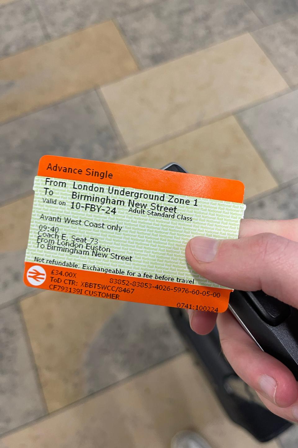 A hand holding a train ticket for travel from London Underground Zone 1 to Birmingham New Street on 10-FBY-24, valid only on Avant West Coast only in Standard Class