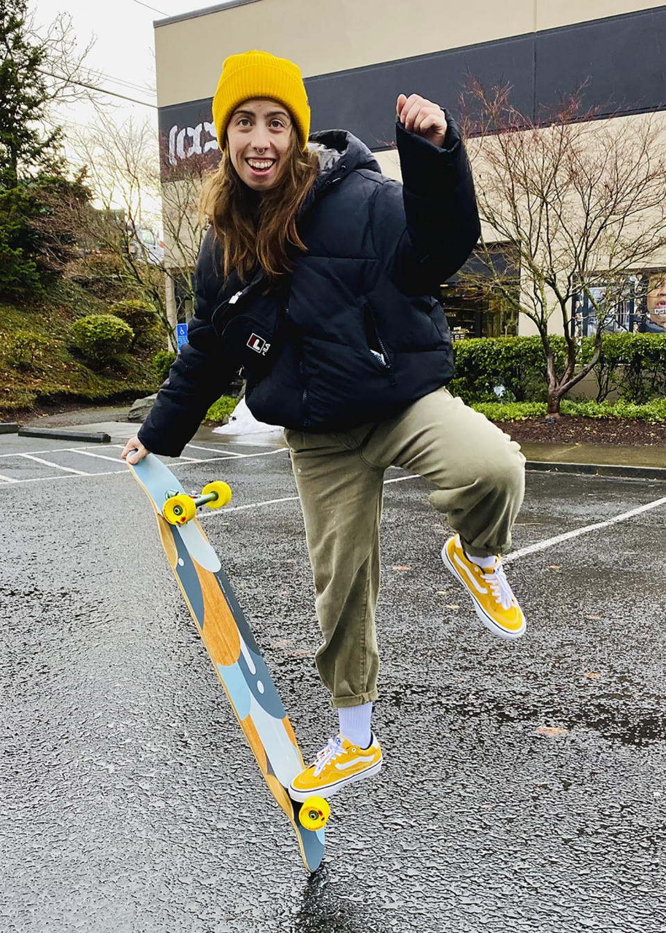 Hannah Dooling poses with her longboard outside Daddies Board Shop in Portland, Ore., in December 2021. Longboard dancing is still in its infancy. But fans say the skate/dance hybrid has already spread in southern California, Paris, Seoul and other places with public squares or wide, open sidewalks. (Devon Hubner, via AP)