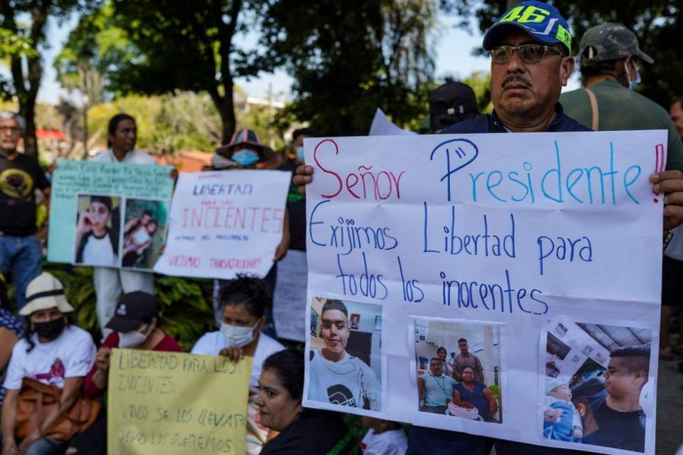 Un manifestante sostiene una pancarta pidiendo la libertad de sus familiares encarcelados durante una protesta contra el estado de emergencia decretado por el presidente Nayib Bukele. El gobierno salvadoreño estableció un estado de emergencia de un año para combatir las pandillas, dejando a más de 66 mil encarcelados. Las organizaciones de derechos humanos afirman que hasta el 10% de los salvadoreños encarcelados podrían ser encarcelados injustamente.