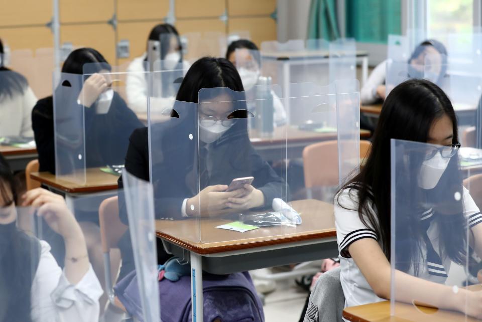 Students sit at their desks separated by plastic shields while waiting for classes to begin at Jeonmin High School, as schools have been reopened to high school students after being closed due to safety concerns over the coronavirus pandemic.