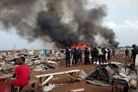 Security forces watch as residents burn dwellings in an impoverished neighborhood in Accra, Ghana, June 20, 2015. REUTERS/Staff