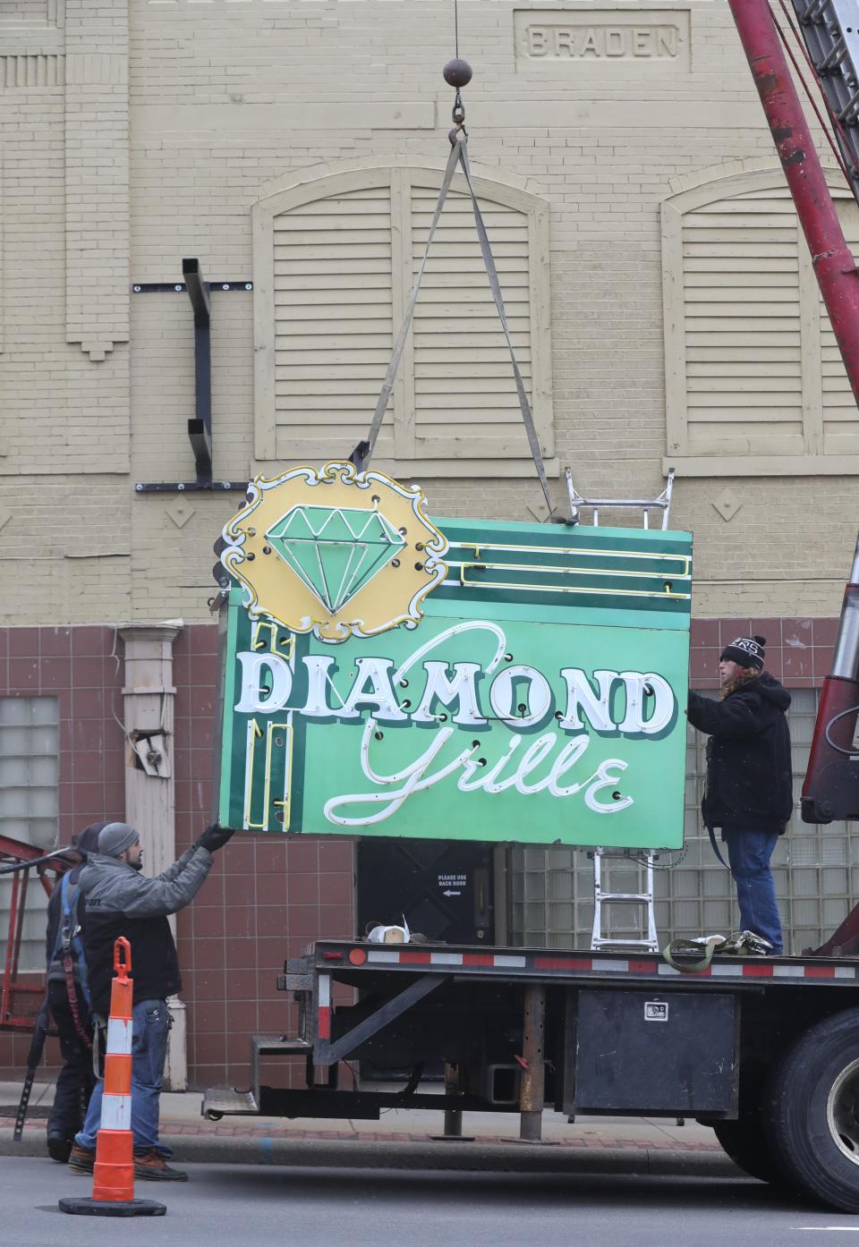 Workers from Adams Signs hoist the refurbished iconic sign of the Diamond Grille in Akron.