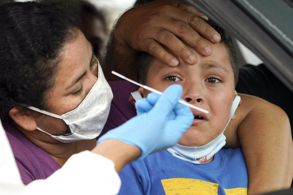 Lillian Palacios, left, holds her son, Daniel, 7, as a healthcare professional prepares to take a sample from him at a United Memorial Medical Center COVID-19 testing site Friday, June 26, 2020, in Houston. (David J. Phillip/AP)