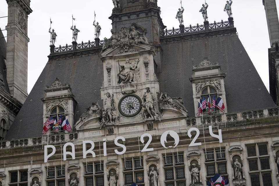 The logo of the Paris 2024 Olympic Games hangs from the facade of the Paris city hall, Wednesday, July 3, 2024 in Paris. Just three weeks before the Olympics, the excitement that was building up in the host city has mingled with anxiety about France’s political future. (AP Photo/Thibault Camus)