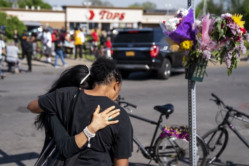 BUFFALO, NY - MAY 15: Jeanne LeGall, of Buffalo, hugs Claudia Carballada, of Buffalo, as she gets emotional, as she pays her respects at an makeshift memorial as people gather at the scene of a mass shooting at Tops Friendly Market at Jefferson Avenue and Riley Street on Sunday, May 15, 2022 in Buffalo, NY. The fatal shooting of 10 people at a grocery store in a historically Black neighborhood of Buffalo by a young white gunman is being investigated as a hate crime and an act of "racially motivated violent extremism," according to federal officials. (Kent Nishimura / Los Angeles Times)