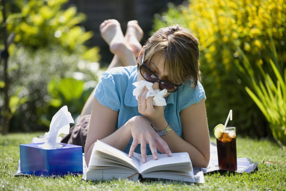 A woman suffering from hay fever, flu, COVID or allergies while sunbathing in her garden. (Photo via Getty Images)