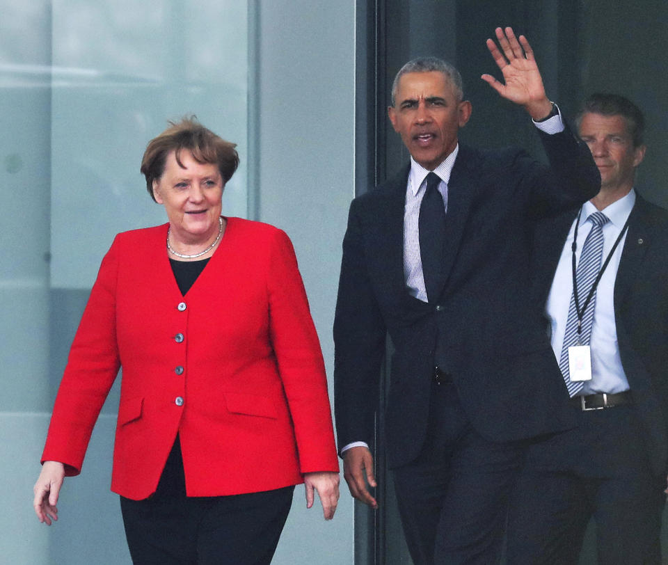 Former US President Barack Obama, right, waves as he and German Chancellor Angela Merkel, left, leave the Chancellery after a meetin in Berlin, Germany, Friday, April 5, 2019. (AP Photo/Michael Sohn)