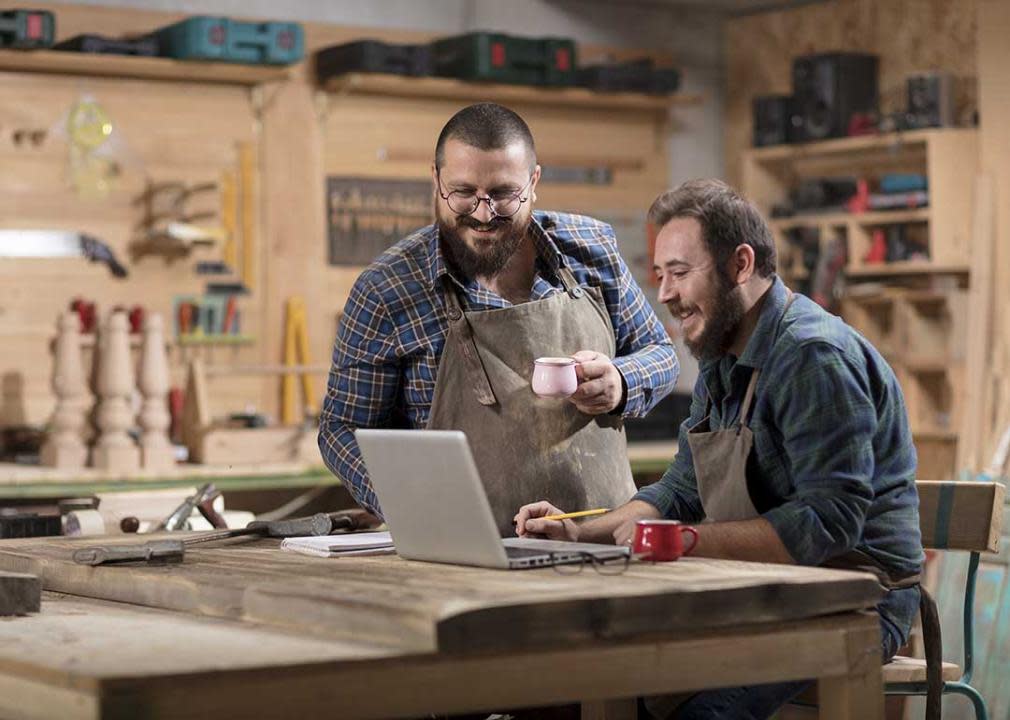 two men in a woodworking shop have a meeting with computer