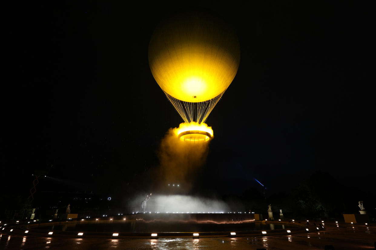 Teddy Riner and Marie-Jose Perec watch as the cauldron rises in a balloon in Paris, France, during the opening ceremony of the 2024 Summer Olympics, Friday, July 26, 2024. (AP Photo/David Goldman)