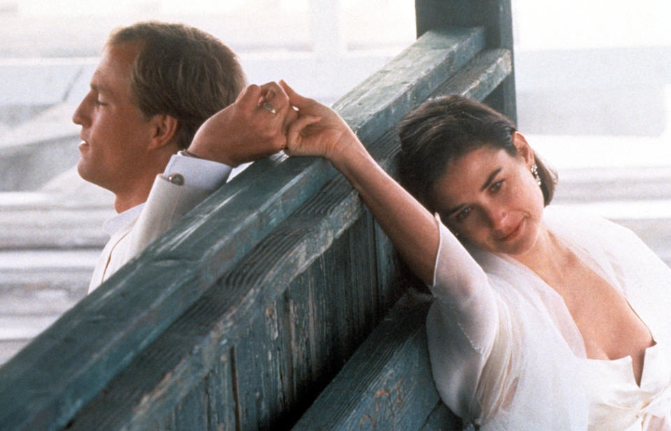 Woody Harrelson and Demi Moore locking fingers from over a wooden partisan in a scene from the film 'Indecent Proposal', 1993. (Photo by Paramount Pictures/Getty Images)