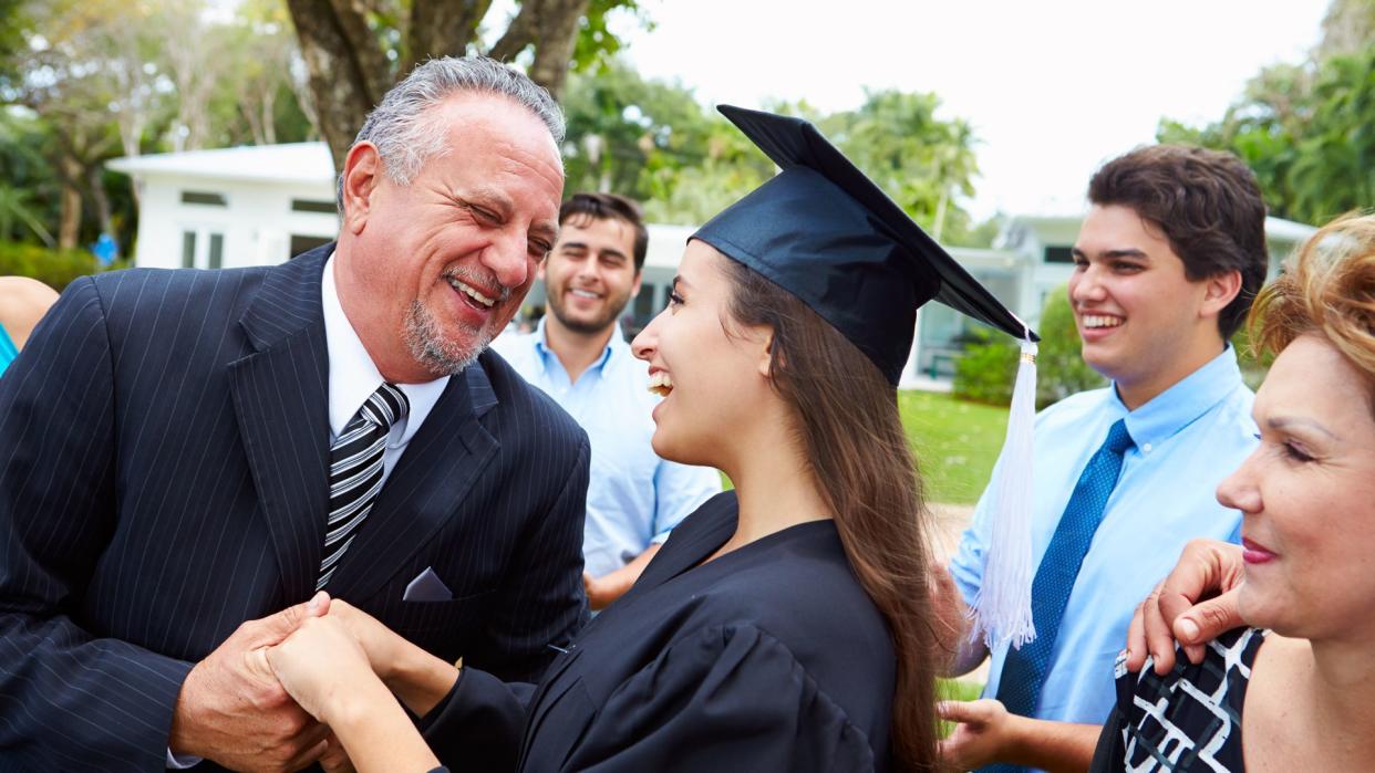 Hispanic Student And Family Celebrating Graduation Smiling.