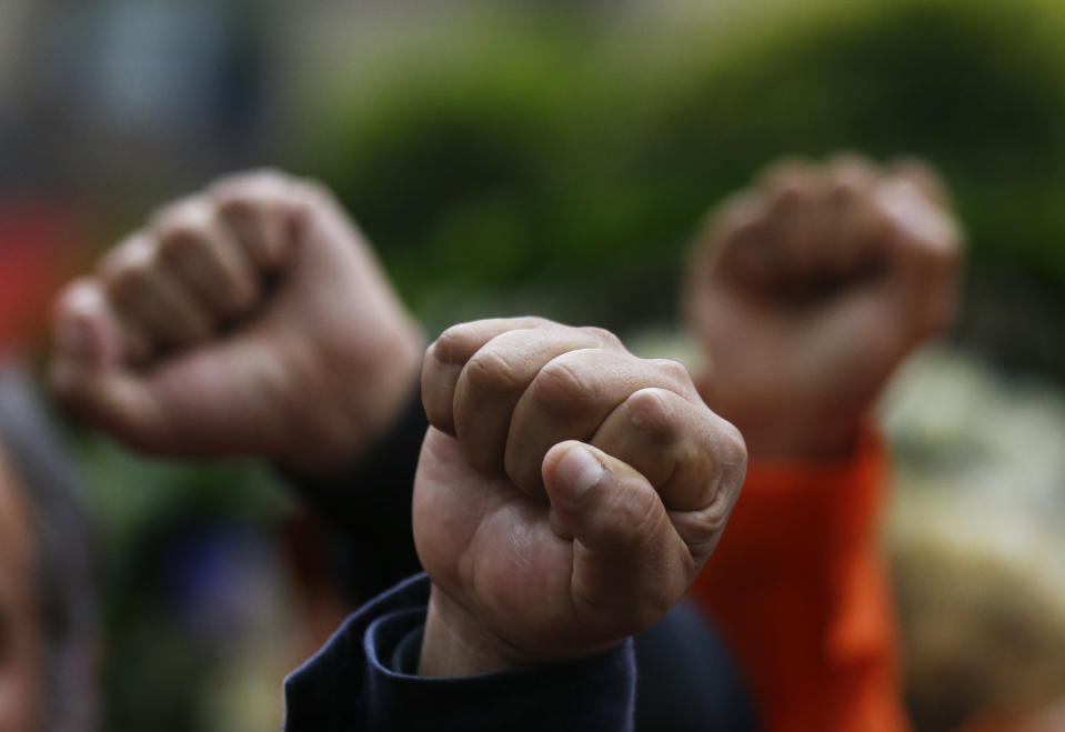 Rescue workers stand with with raised fists and in silence, in front of a 1985 earthquake memorial during a ceremony marking that quake's 33rd anniversary and last year's 7.1 magnitude earthquake, in Mexico City, Wednesday, Sept. 19, 2018. The rescue workers, known as "topos," are a voluntary civil brigade, who were created during the 1985 earthquake that left at least 9,500 dead. (AP Photo/Marco Ugarte)