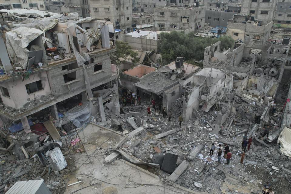 Palestinians walk around destroyed buildings