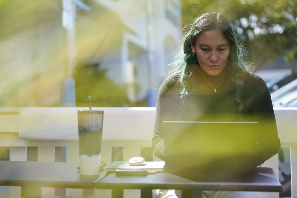 Daniella Malave works on her laptop at a coffee shop in Sea Girt, N.J., Thursday, Sept. 29, 2022. While working full time for Chipotle, Malave completed two years of community college with annual stipends of $5,250 from the restaurant chain. After that, she enrolled in the company’s free online college program, through which she earned a bachelor’s degree in business management from Wilmington University in 2020. (AP Photo/Seth Wenig)