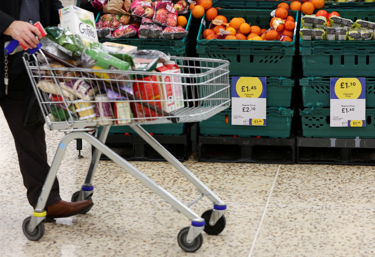A person pushes a shopping cart next to the clubcard price branding inside a branch of a Tesco Extra Supermarket in London, Britain, February 10, 2022. Picture taken February 10, 2022. REUTERS/Paul Childs