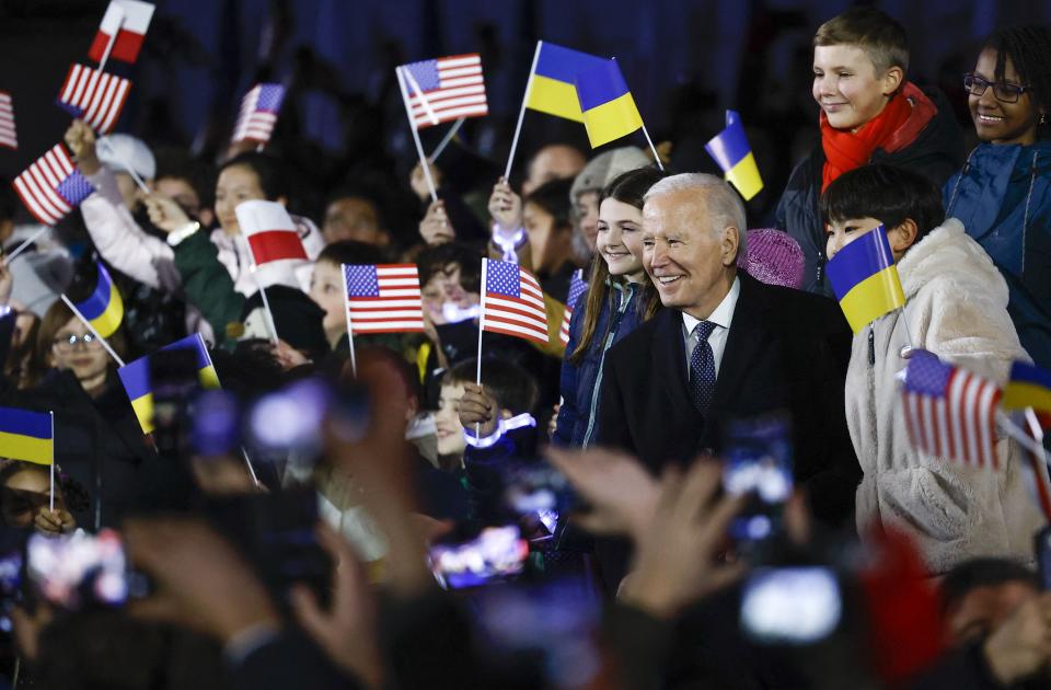 President Joe Biden stands amid children cheering with U.S., Polish and Ukrainian flags after he delivered a speech in Warsaw, Poland on Feb. 21, 2023.