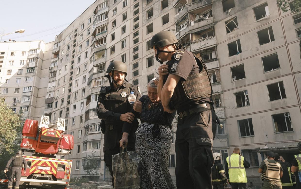 Two firefighters help an elderly woman