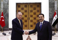 Iraqi Prime Minister Mohammed Shia al-Sudani, right, and Turkish President Recep Tayyip Erdogan shake hands in Baghdad, Iraq, Monday April 22, 2024. (Turkish Presidency via AP)