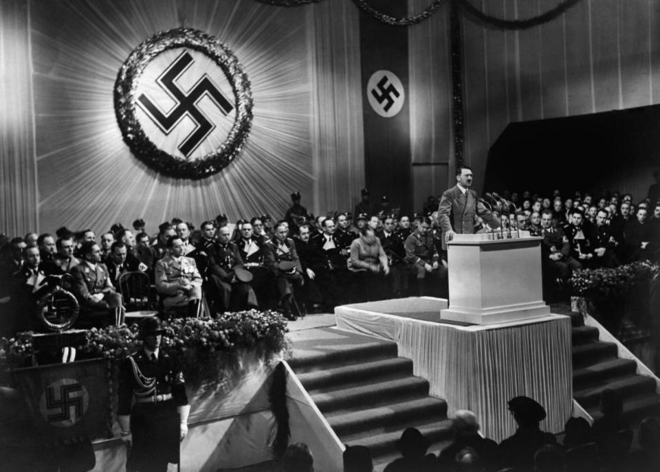 <div class="inline-image__caption"><p>Nazi dictator Adolf Hitler giving a speech during a meeting with Nazi high-ranking officials seated under a large swastika in 1939. </p></div> <div class="inline-image__credit">AFP via Getty</div>