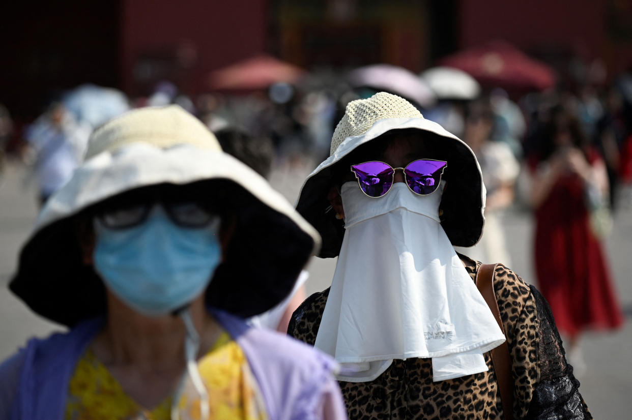 A woman shelters under a mask as she walks out of the Forbidden City during hot weather conditions in Beijing (Wang Zhao / AFP via Getty Images file )