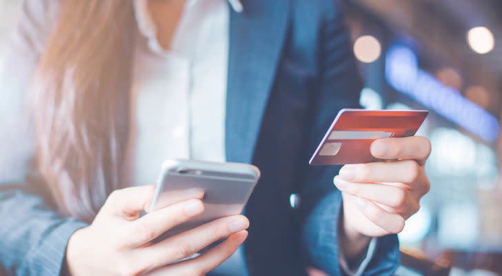 a person holding an iphone in one hand and a credit card in the othr