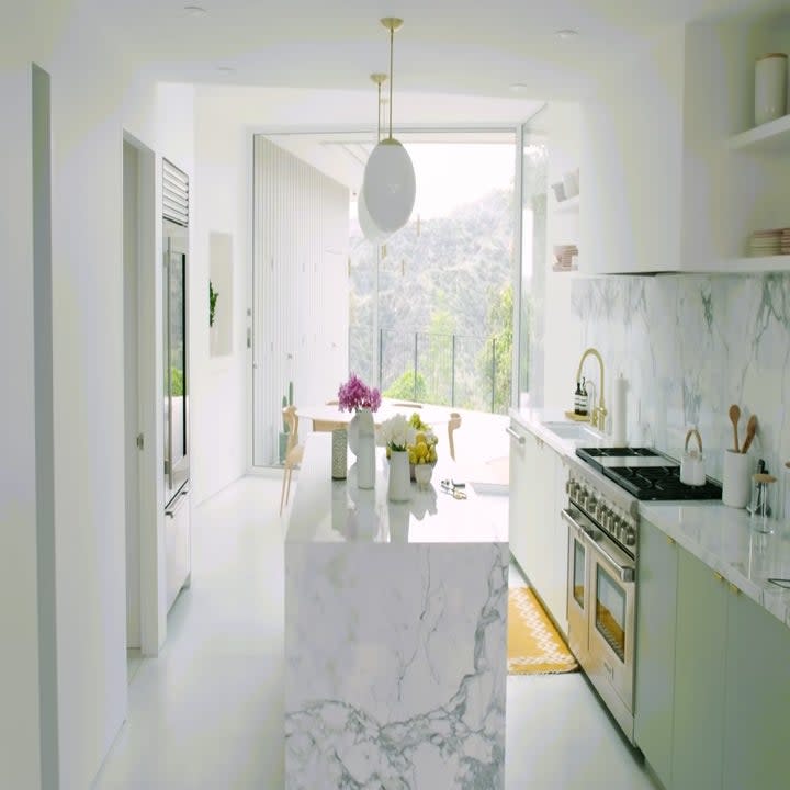 The kitchen has a marble island, marble countertop, and a marble back wall