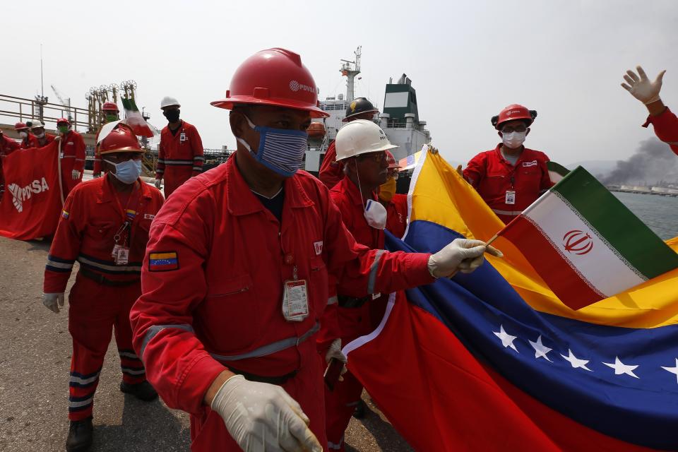 Un trabajador petrolero venezolano con una pequeña bandera iraní asiste a una ceremonia por la llegada del petrolero iraní Fortune a la refinería El Palito cerca de Puerto Cabello, Venezuela, el lunes 25 de mayo de 2020. (Foto AP / Ernesto Vargas)