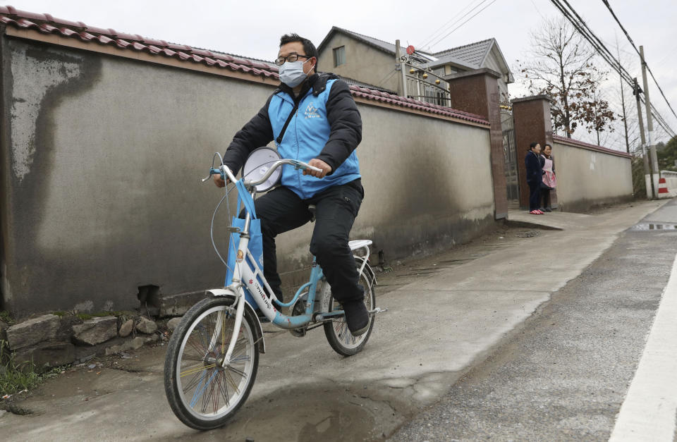 A community health worker rides a bicycle while carrying a loudspeaker broadcasting virus control information in Hangzhou in eastern China's Zhejiang Province, Monday, Jan. 27, 2020. China on Monday expanded sweeping efforts to contain a viral disease by extending the Lunar New Year holiday to keep the public at home and avoid spreading infection. (Chinatopix via AP)