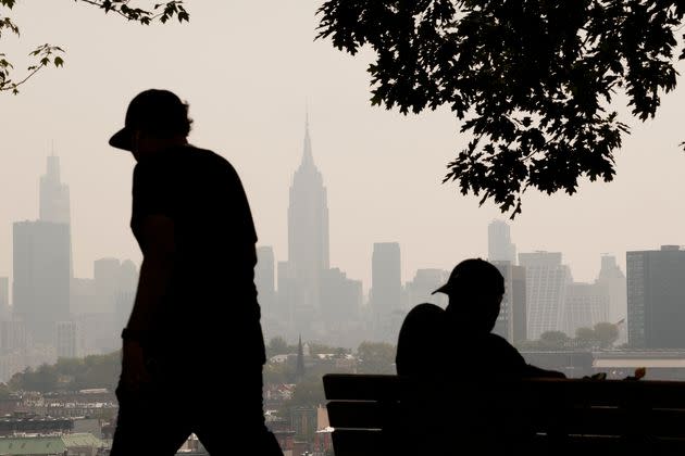 Haze caused by smoke from wildfires in Canada shrouds the New York City skyline as a man sits in a park on July 18 in Jersey City, New Jersey.
