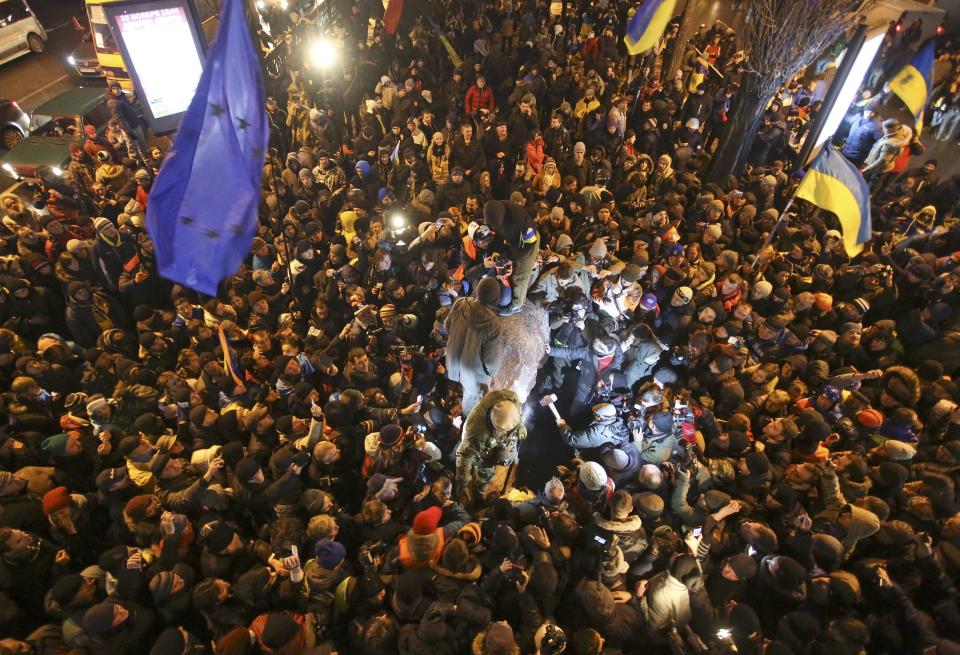 People surround a statue of Soviet state founder Vladimir Lenin (C), which was toppled by protesters during a rally organized by supporters of EU integration in Kiev, December 8, 2013. Crowds toppled a statue of Soviet state founder Vladimir Lenin in the Ukrainian capital and attacked it with hammers on Sunday in the latest mass protests against President Viktor Yanukovich and his plans for closer ties with Russia. REUTERS/Maxim Zmeyev (UKRAINE - Tags: POLITICS CIVIL UNREST)