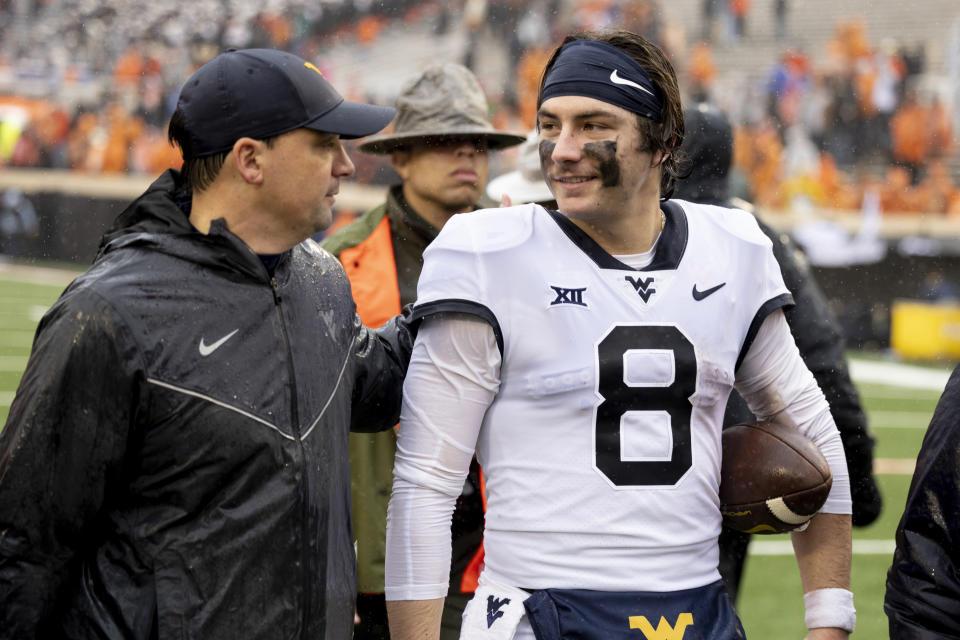 West Virginia head coach Neal Brown talks with quarterback Nicco Marchiol (8) after the NCAA college football game against Oklahoma State in Stillwater, Okla., Saturday Nov. 26, 2022. (AP Photo/Mitch Alcala)