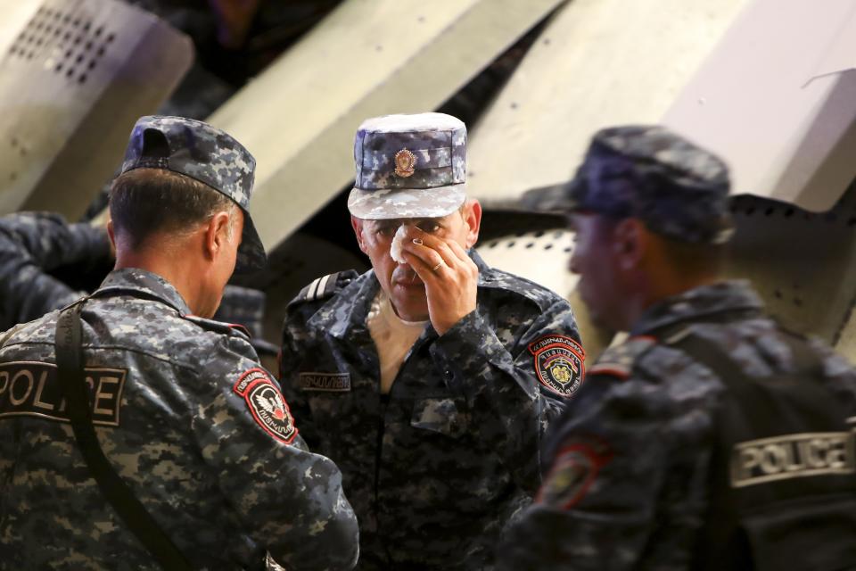 Police officers defense their injured comrade as they block an entrance of the government building during a protest against Prime Minister Nikol Pashinyan in Yerevan, Armenia, on Wednesday, Sept. 20, 2023. Protesters gathered in central Yerevan, the capital of Armenia, blocking streets and demanding that authorities defend Armenians in Nagorno-Karabakh. (Vahram Baghdasaryan/Photolure via AP)