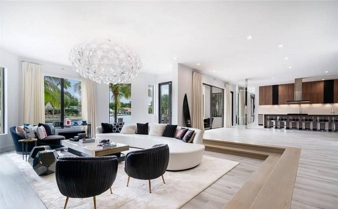 The two-story estate has 10 bedrooms and covers 10,500 square feet. Here is a photo of the living room with a view of the water and pool. Compass Florida, MLS