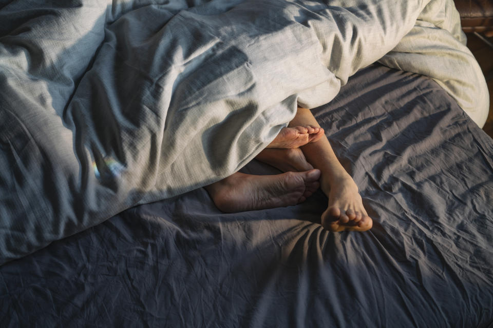 a couple in bed exposing their feet out from the covers