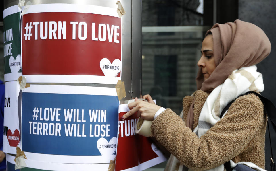 A demonstrator hangs banners from multi-faith group Turn to Love during a vigil at New Zealand House in London.