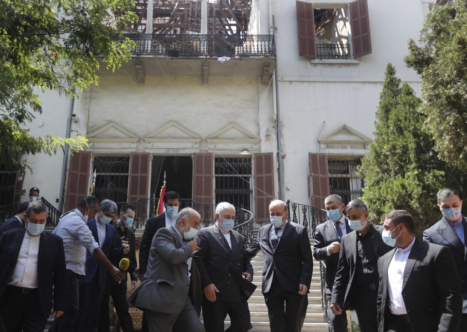 Iranian Foreign Minister Mohammad Javad Zarif, center left, and his Lebanese counterpart Charbel Wehbe, center right, walk outside the Lebanese Foreign Ministry which damaged by last week's explosion that hit the seaport of Beirut, Lebanon, Friday, Aug. 14, 2020. (AP Photo/Hussein Malla)