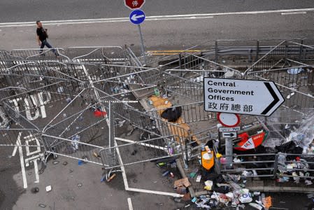 A man walks past barriers surrounding the Legislative Council building after violent clashes during a protest against extradition bill, in Hong Kong