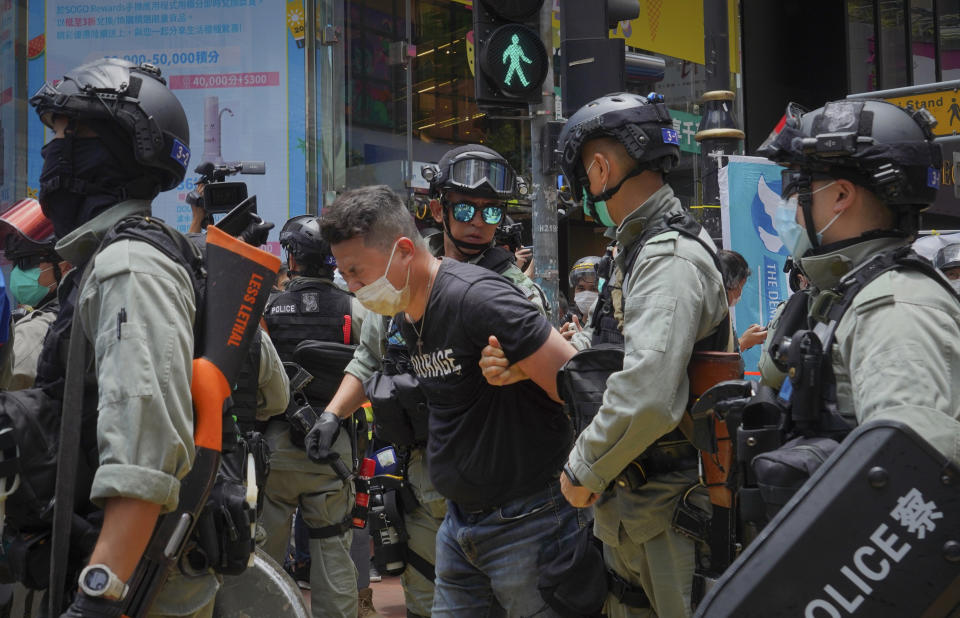 Police detain a protester after spraying pepper spray during a protest in Causeway Bay before the annual handover march in Hong Kong, Wednesday, July. 1, 2020. Hong Kong marked the 23rd anniversary of its handover to China in 1997, and just one day after China enacted a national security law that cracks down on protests in the territory. (AP Photo/Vincent Yu)