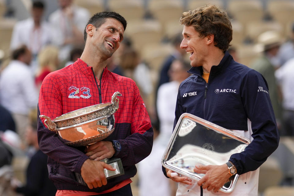 FILE - Serbia's Novak Djokovic, left, celebrates winning the men's singles final match of the French Open tennis tournament against Norway's Casper Ruud, right, in three sets, 7-6, (7-1), 6-3, 7-5, at Roland Garros stadium in Paris, Sunday, June 11, 2023. His ability to read someone else's intentions, get to where a ball is headed and send it back with force, a combination Casper Ruud described this way after losing to Djokovic in the French Open final: "He sort of just goes into this mode where he just becomes, like, a wall." (AP Photo/Thibault Camus, File)