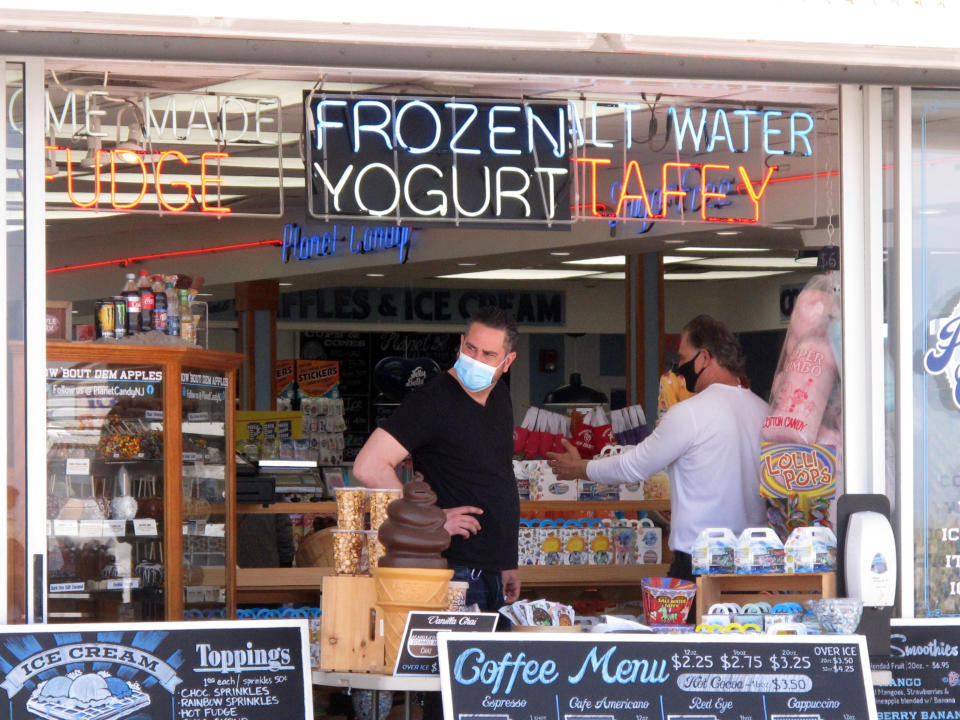 An employee waits for customers at a boardwalk candy store in Seaside Heights, N.J. on Friday, May 15, 2020 on the first day the beach and boardwalk opened during the coronavirus outbreak. It and another popular Jersey Shore beach, Point Pleasant Beach, were among those allowing people back onto the sand with some restrictions to try to slow the spread of the virus. (AP Photo/Wayne Parry)