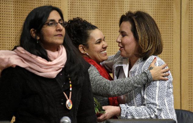 Seattle City Council member Debora Juarez, right, is embraced by Rachel Heaton, a Muckleshoot tribal member, as Council member Kshama Sawant stands nearby after Heaton gave both women gifts from the Native American community before a Council meeting Tuesday, Feb. 7, 2017, in Seattle. The City Council is scheduled to vote on whether to divest $3 billion in city funds from Wells Fargo over its funding of the Dakota Access Pipeline. (AP Photo/Elaine Thompson)