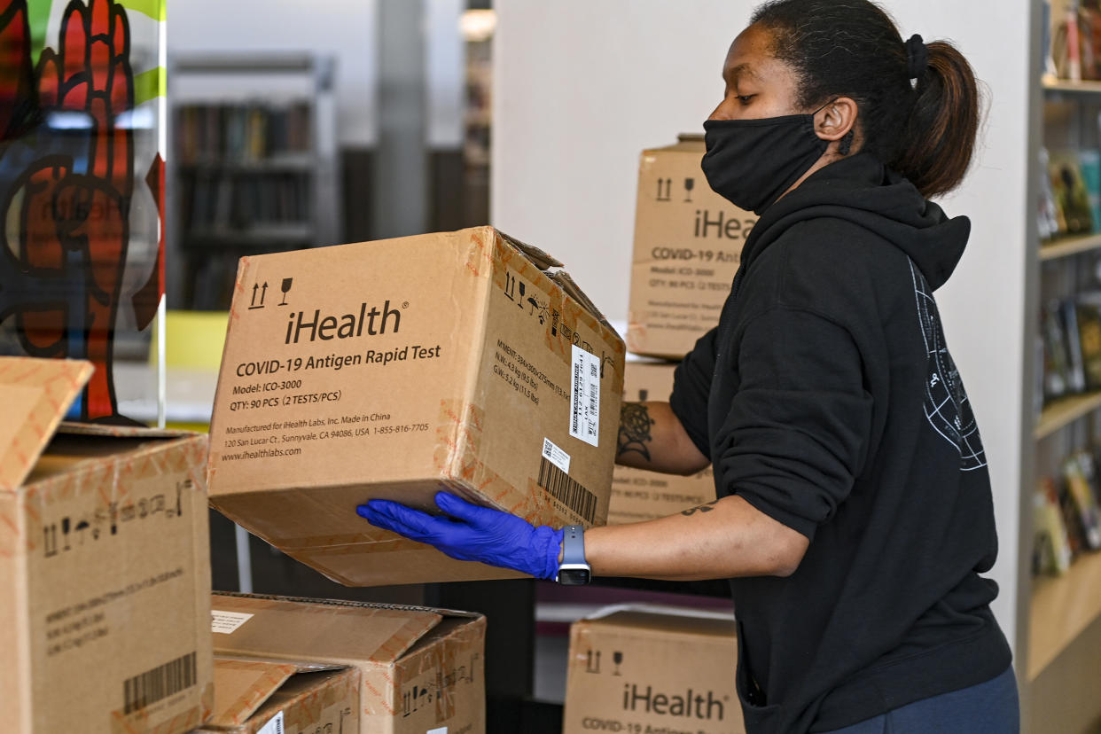 Cajas con kits de pruebas de COVID-19 son clasificadas antes de ser repartidas en la Biblioteca Anacostia en Washington, el 29 de diciembre de 2021. (Kenny Holston/The New York Times).