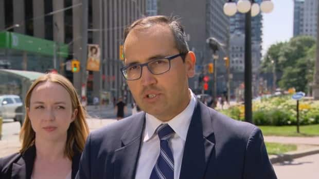 Lawyer Nader Hasan speaking with members of the media Friday afternoon. He's accompanied by lawyer Ryann Atkins. (CBC - image credit)