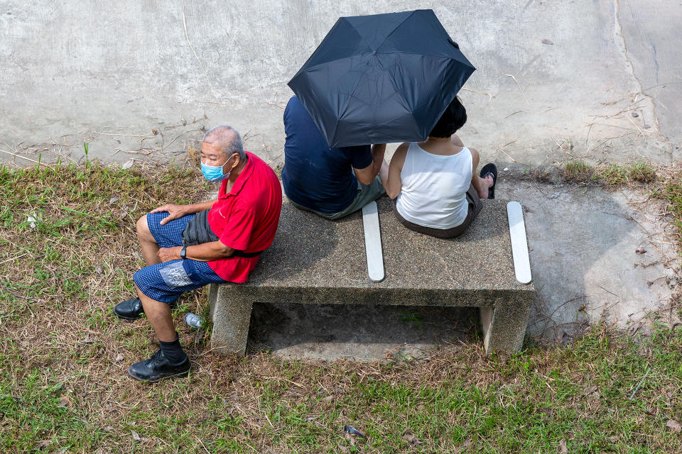 An elderly man in a face mask shares a bench with a couple. (PHOTO: Dhany Osman / Yahoo News Singapore)