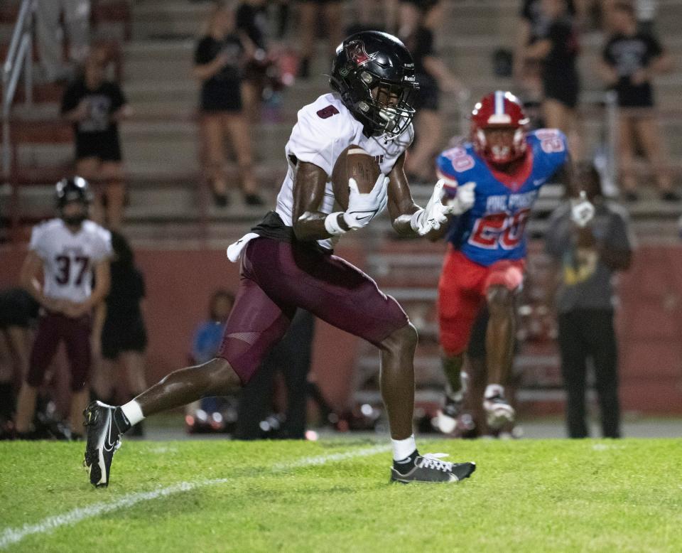 Navarre High's Tyrell Marshall (No. 5) gains control of the ball as he runs for extra yards against the Pine Forest defense on Friday, September 1, 2023.