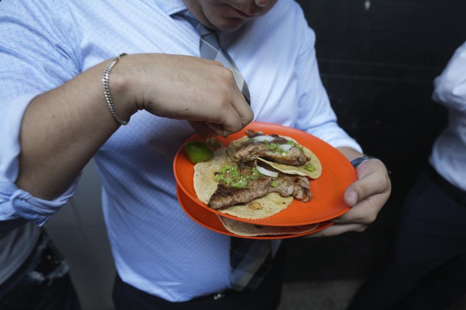 Un cliente exprime un limón en sus tacos en la taquería Tacos El Califa de León en Ciudad de México, el miércoles 15 de mayo de 2024. Tacos El Califa de León es la primera taquería en recibir una estrella Michelin. (AP Foto/Fernando Llano)